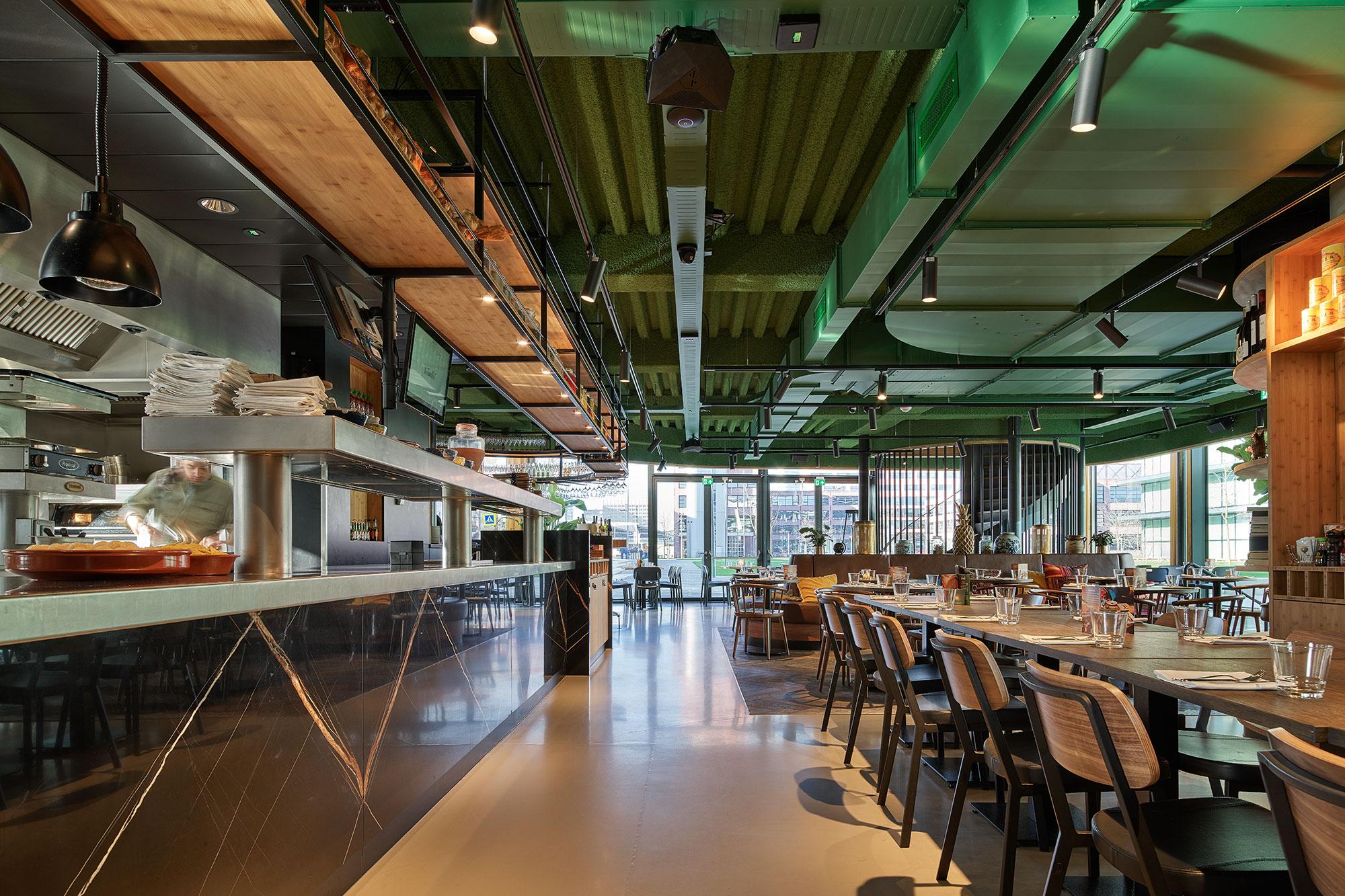 Groen akoestisch spuitplafond in The Traveller Zuidoost, geeft een frisse en moderne sfeer aan de ruimte boven de trap.