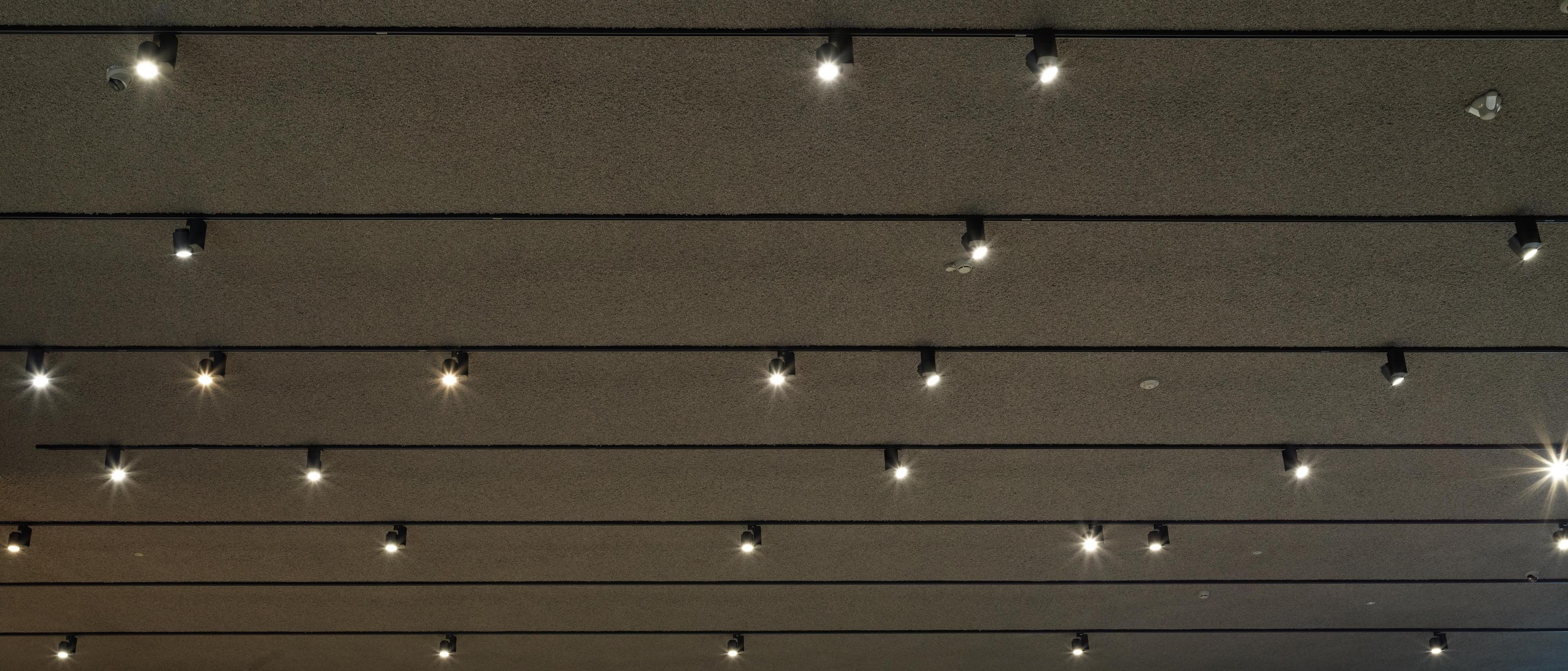 Naadloos akoestisch spuitwerk aangebracht op betonnen plafond — Acosorb® Close up van Audi showroom met spotjes en vlokken plafond van Acosrob