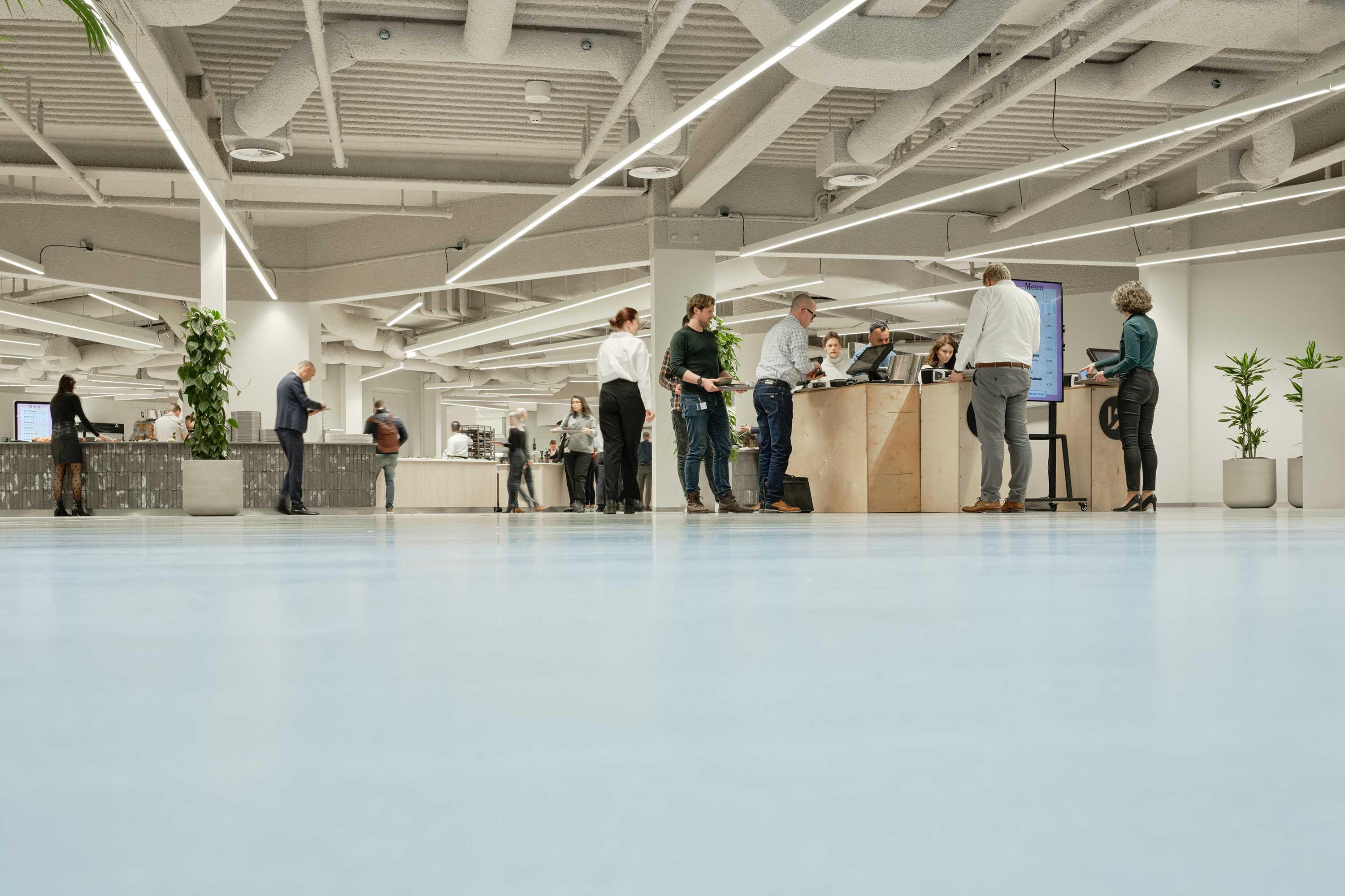 Group of people standing and talking inside a modern building with high ceiling