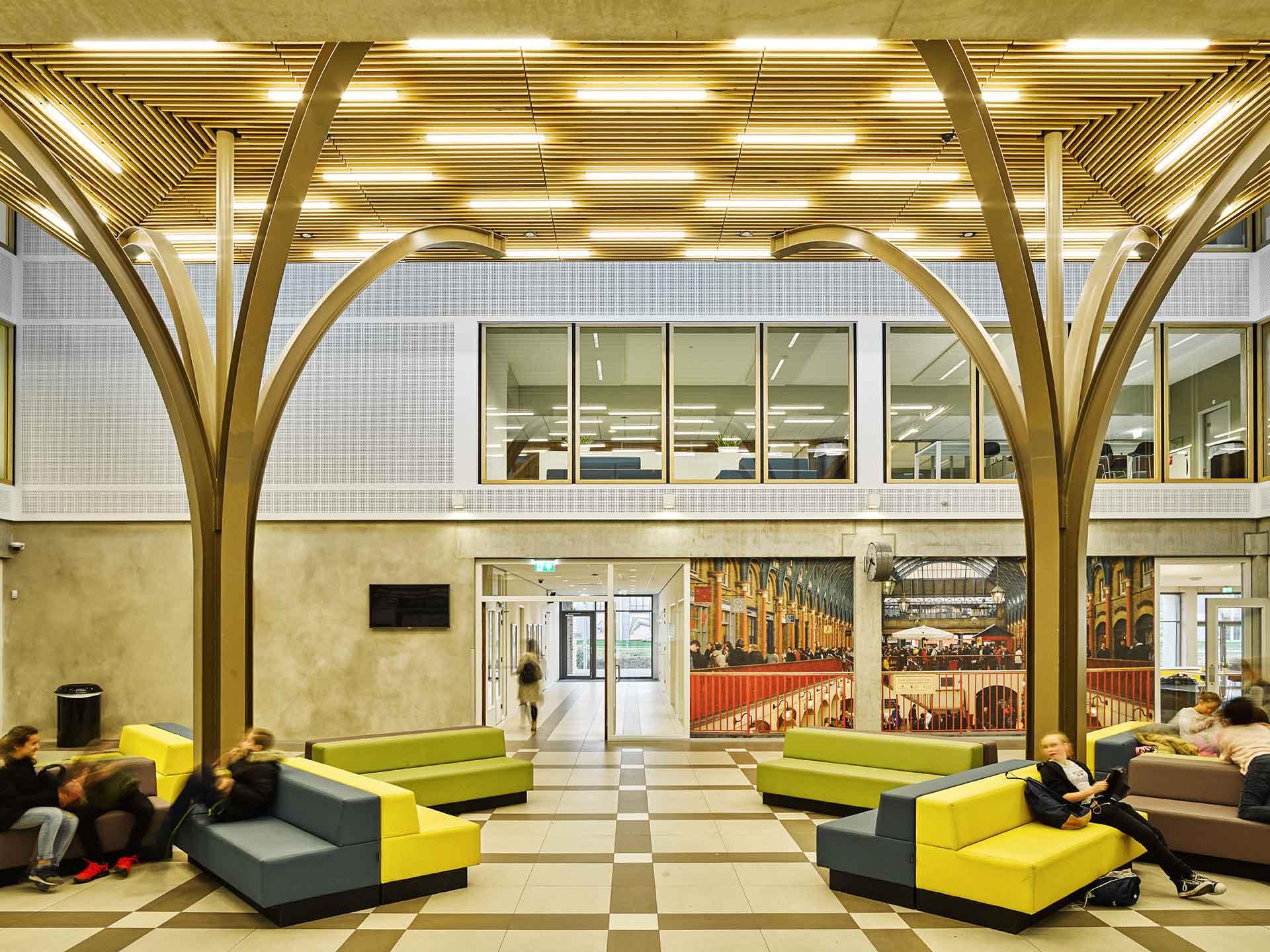 Atrium of Melanchthon school with wooden tree-like acoustic ceiling and colorful lounge chairs